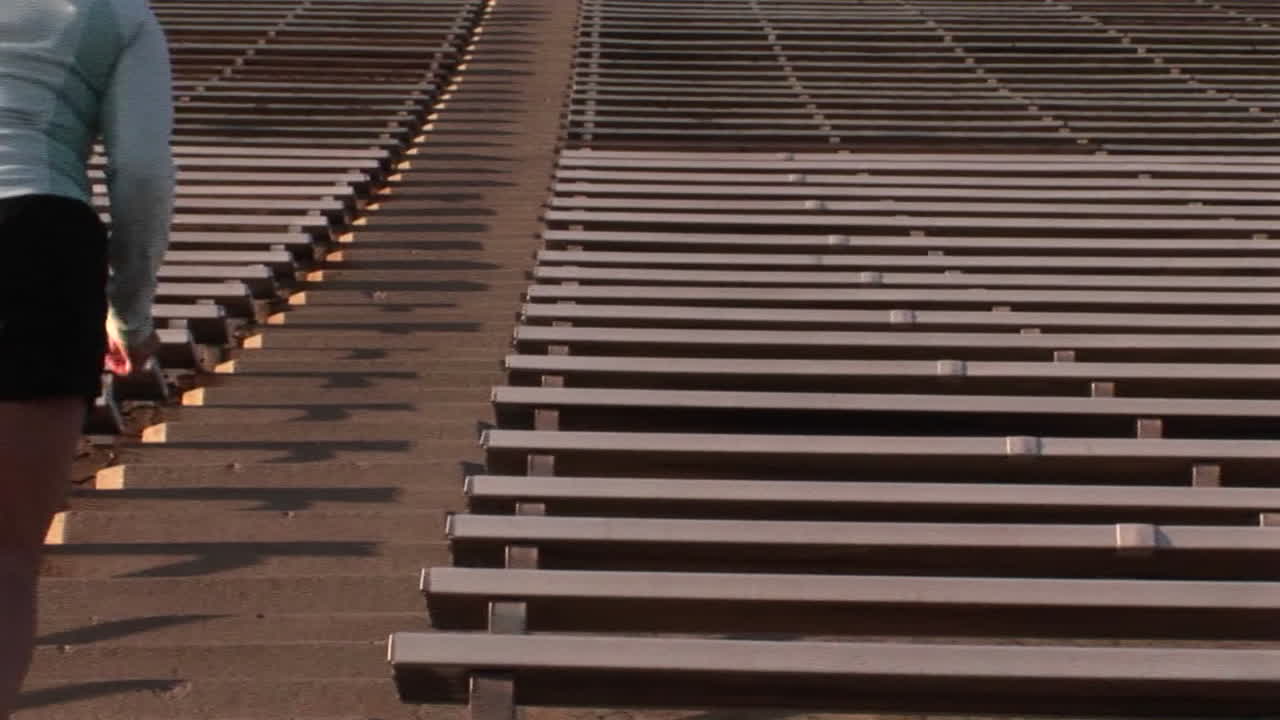 큰 경기장의 계단을 뛰어 오르는 여자의 왼쪽 게