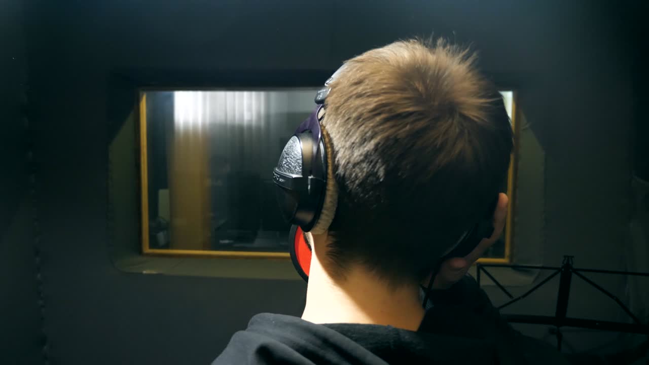 헤드폰을 착용한 남성 가수가 사운드 스튜디오에서 노래를 부르고, 감정적으로 노래를 녹음하는 젊은이, 창의적인 뮤지션의 작업, 쇼 비즈니스 개념, 슬로 모션 뒷면 뒷면