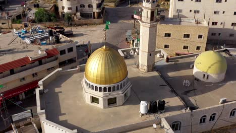 aerial view of a mosque with a golden dome and minaret in a town