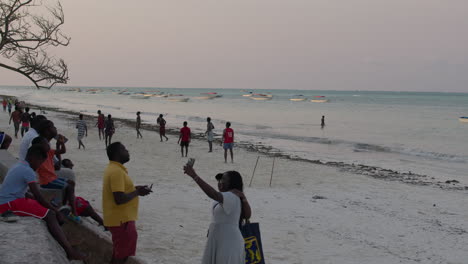 locals and tourists walk on the beach of zanzibar island at sunset.
