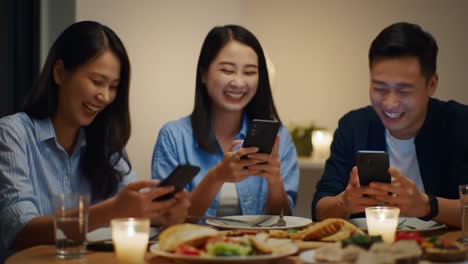 joyful friends sharing moments over dinner with smartphones: laughter and connection illuminate the evening as they enjoy food and technology together