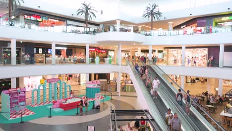daily life wide view shot of shoppers at saler shopping mall as they ride escalators and visit multinational brand stores in valencia, spain.