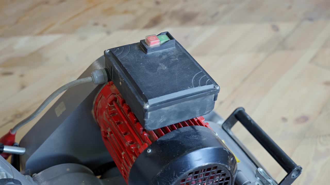Worker presses red button on sanding machine to power it off after use