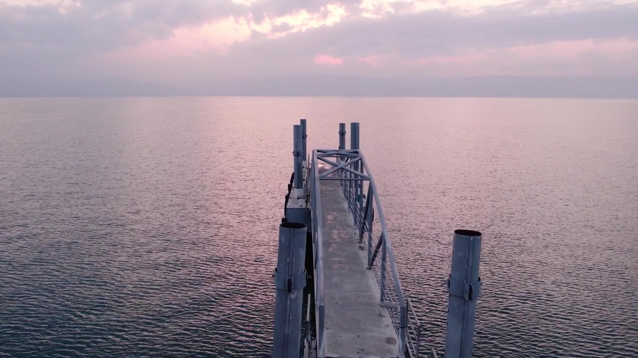 Peaceful Aerial View of a Pier Extending into Calm Water at Sunset