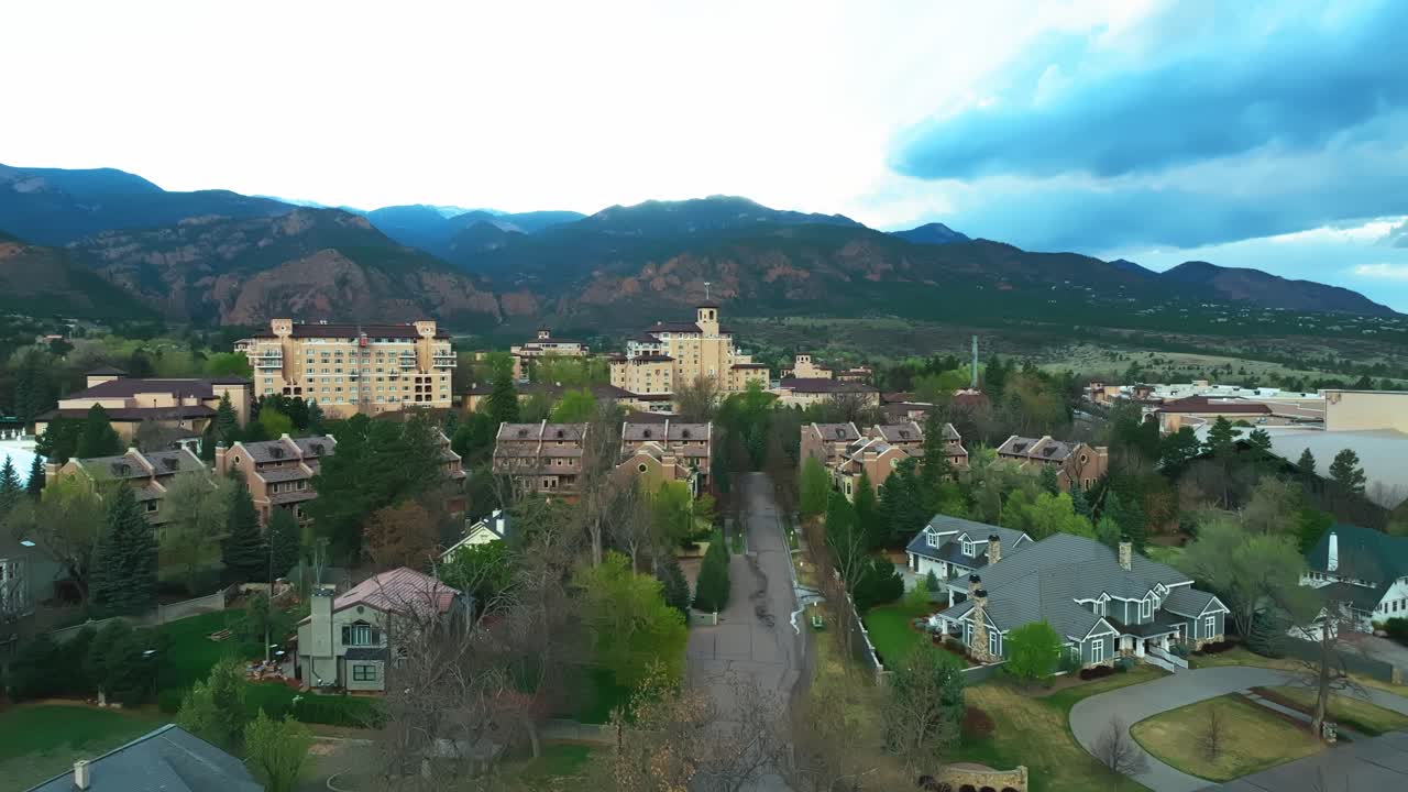Broadmoor hotel framed by green forest and blue sky, calm summer view