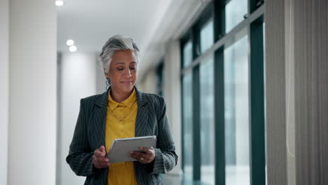 mature businesswoman using a tablet in a modern office corridor
