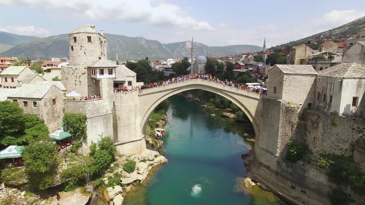 un hombre hace un salto de bala de cañón desde el concurrido puente de mostar en mostar, bosnia