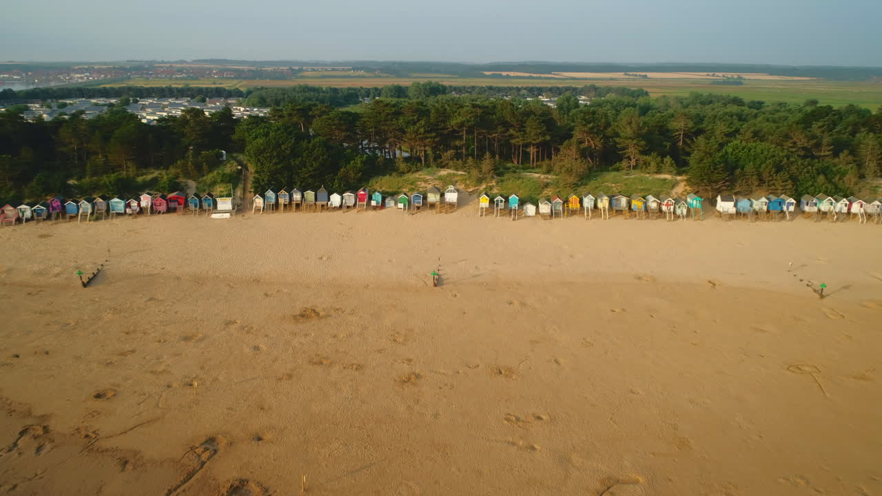 disparo de drones tirando hacia atrás de cabañas de playa frente a la zona boscosa con playa y mar en wells-next-the-sea north norfolk, reino unido costa este