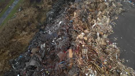 aerial rises in helix movement above huge dumpsite filled with tons of wooden and bulky waste made up of light and dark euro pallets