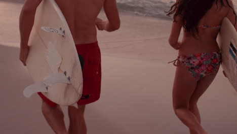 Athletic-couple-running-beside-the-sea-with-surfboards