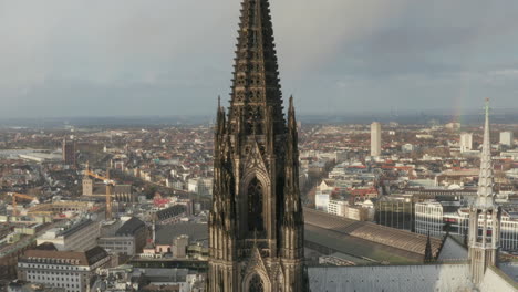 Close-up-footage-of-beautiful-gothic-style-tower-with-decorative-turrets-and-ornaments.-Cathedral-Church-of-Saint-Peter-and-town-development-in-background.-Cologne,-Germany