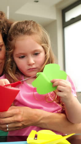 cute mother and daughter doing arts and crafts at kitchen table