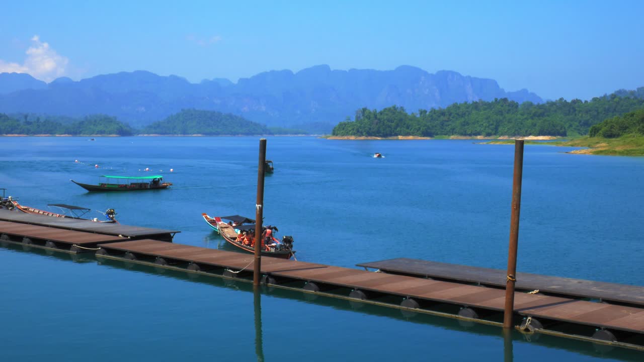 롱테일 보트는 목조 부두 옆 바다에서 수영합니다.