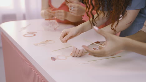 close up view of friends's hands putting cardboard decorations on a white table for bachelorette party celebration