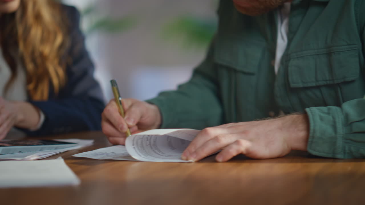 Focused man signing contract shaking hands with businesswoman in office closeup