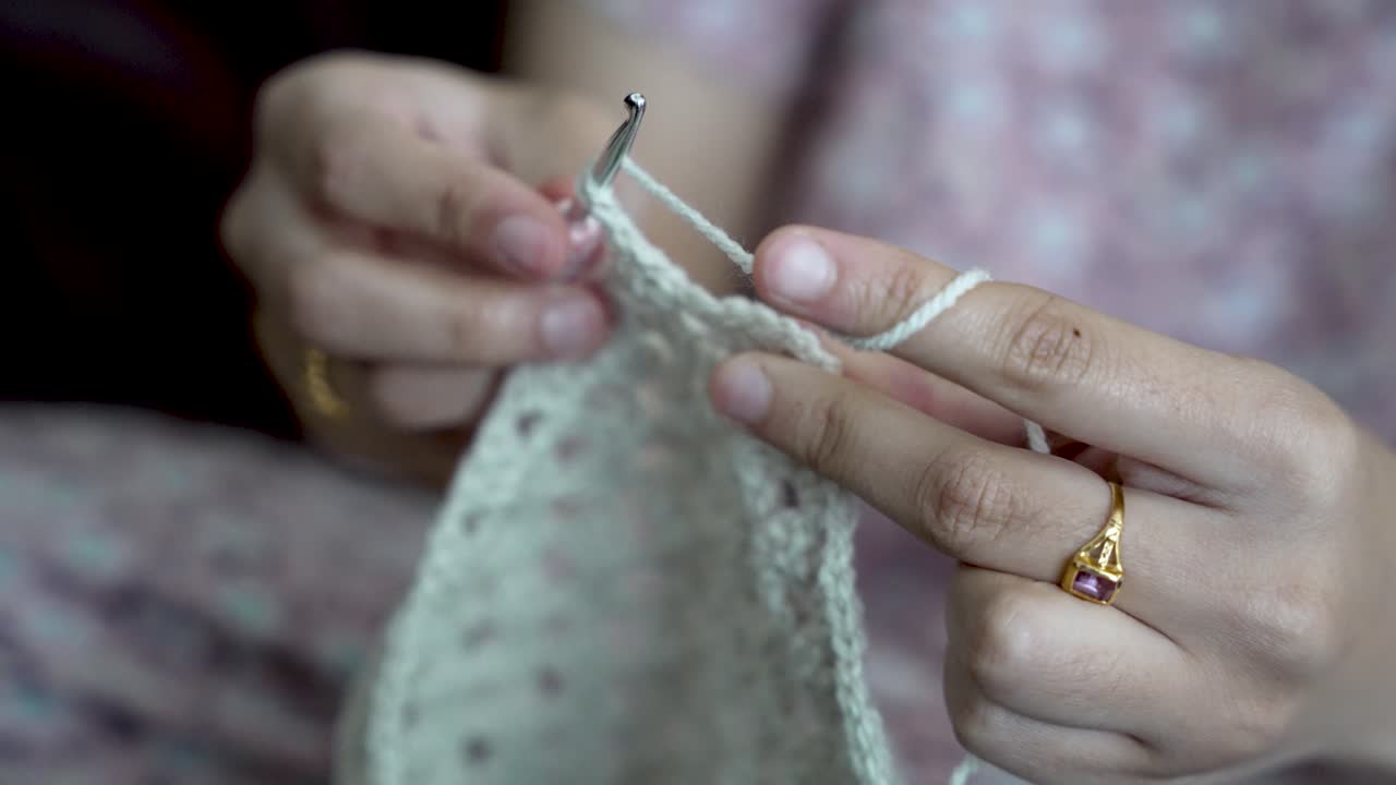 Close up of hands using crochet hook and wool yarn, creating handmade clothes or accessories