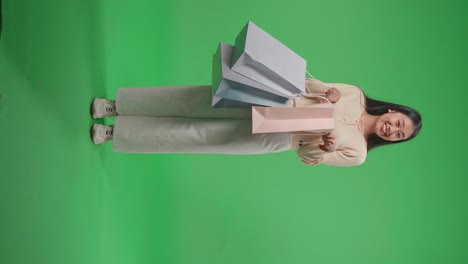 vista completa de una mujer de compras asiática siendo feliz después de abrir la bolsa de compras mientras está de pie frente a la pantalla verde