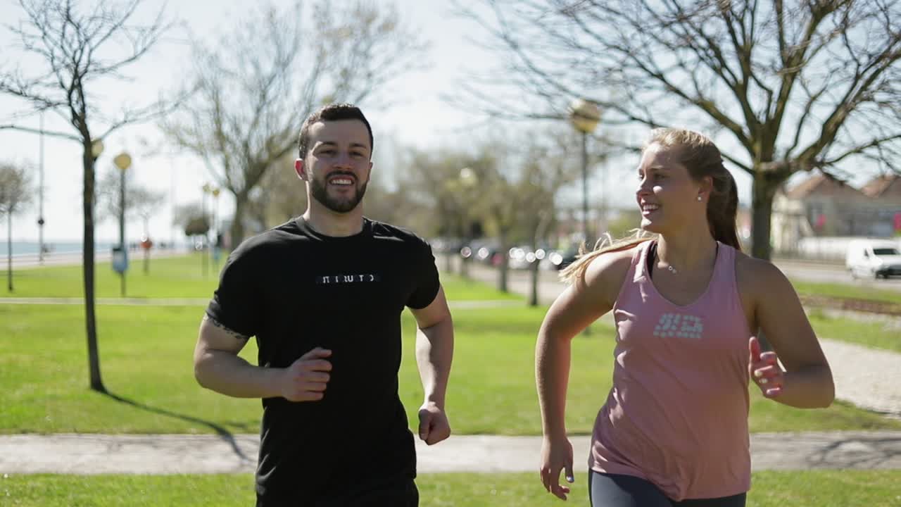 jóvenes sonrientes corriendo en el parque.
