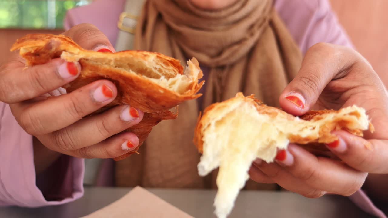 una mujer comiendo un croissant.