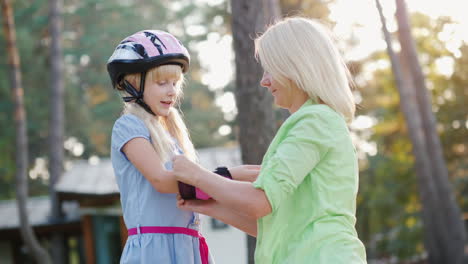 Elternbetreuung-Mama-Kleidet-Töchter-Von-Ellbogenschützern-Zum-Radfahren-Oder-Rollschuhen-4k-Video