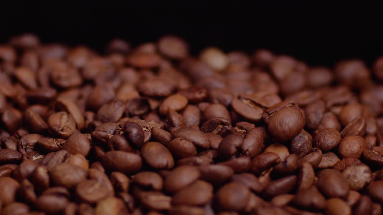 Primo piano di chicchi di caffè che cadono al rallentatore su sfondo nero