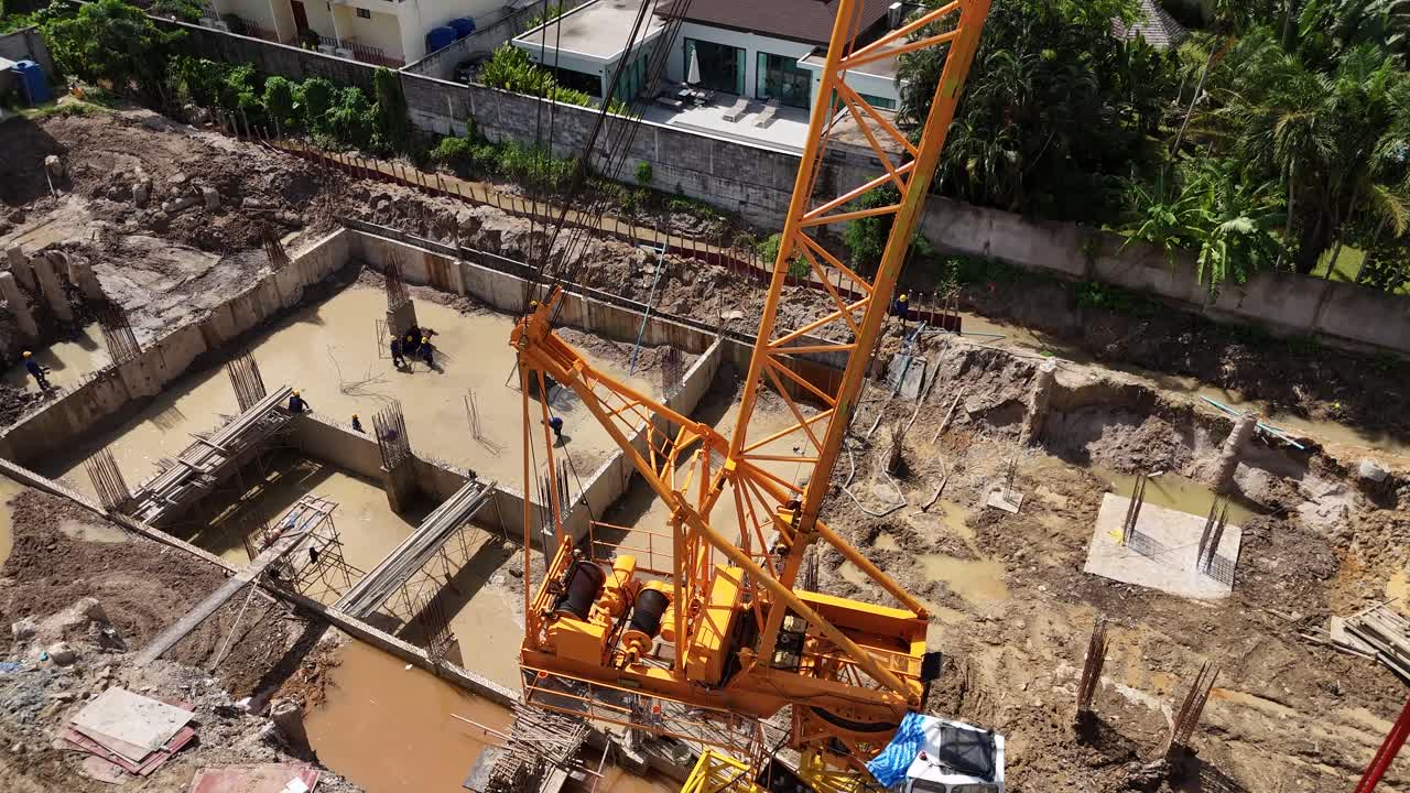 Aerial view of a construction site with a large crane and workers building foundations