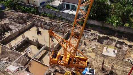 aerial view of a construction site with a large crane and workers building foundations