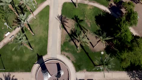 Aerial-forward-drone-shot-of-an-empty-Pedestrian-Avenue-with-a-white-statue-inside-of-a-circle-in-the-middle