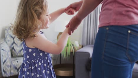 Caucasian-mother-and-daughter-having-fun-dancing-in-living-room