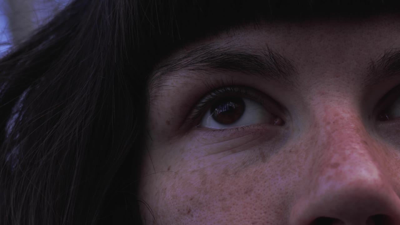 toma cercana de una chica pecosa con cabello castaño y flequillo mientras mira hacia arriba y hacia abajo