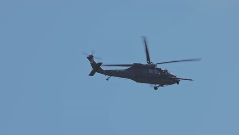 Tracking-shot-of-attacking-military-helicopter-flying-against-blue-sky-during-sunny-day