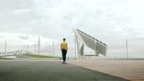 young attractive trendy man skateboarding fast under a solar panel on a morning sunny day with an urban city background in slow motion