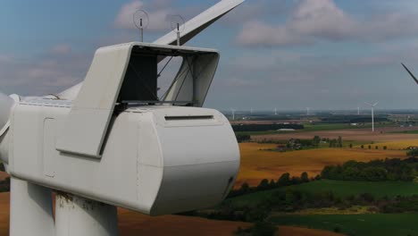 wind turbine close up aerial shot panning around the read with farmland in the background