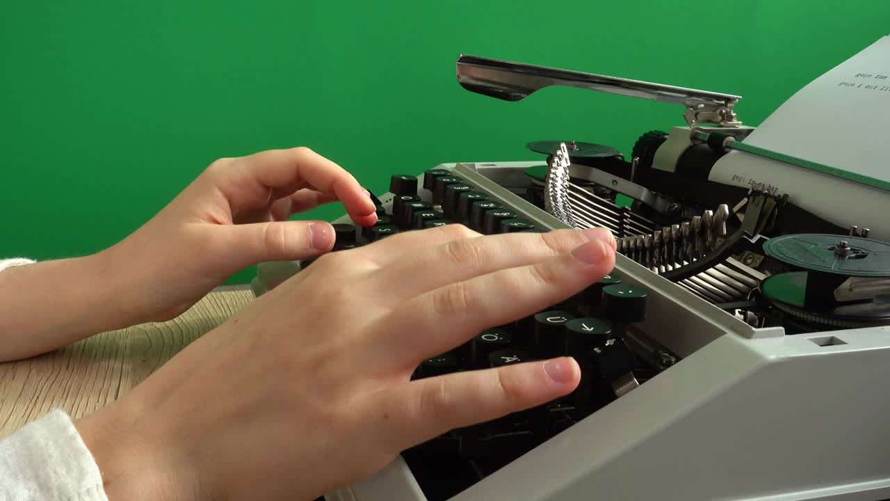 The girl is typing on a retro typewriter on a green background. Chromakey.