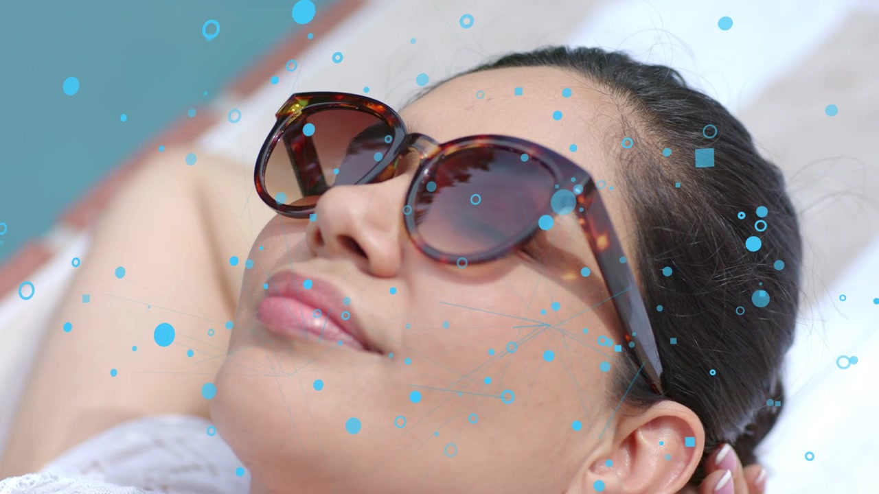 Woman reclining, hand adjusting, camera zooming, blue bubbles drifting over sunglasses for fashion