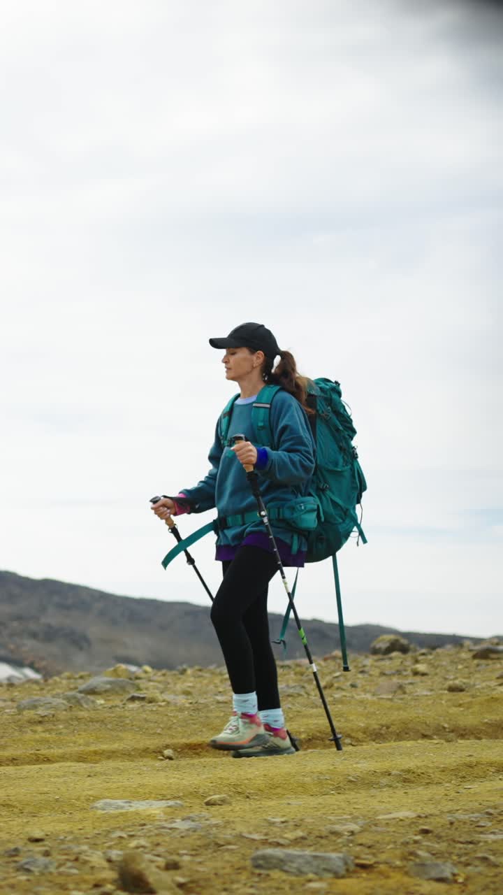 Donna che fa escursioni con zaino e bastoncini da trekking in un paesaggio montano