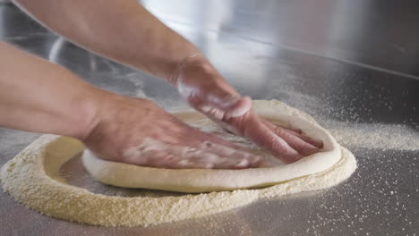 vista de cerca de las manos de un chef amasando masa de pizza en la encimera de la cocina de un restaurante 2