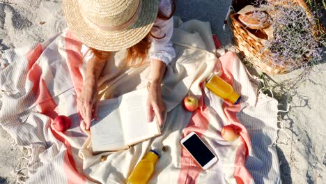 hands of girl lying on a beach and reading a book