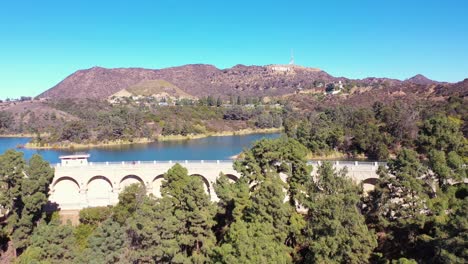 aerial along the dam at the hollywood reservoir in the hollywood hills with hollywood sign distant