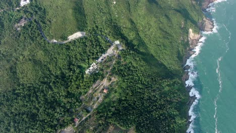 Aerial-view-of-a-jagged-rock-island,-surrounded-with-lush-green-nature-and-Hong-Kong-bay-water