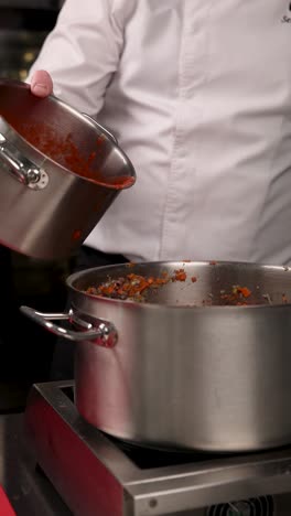 chef pouring tomato sauce into stew pot