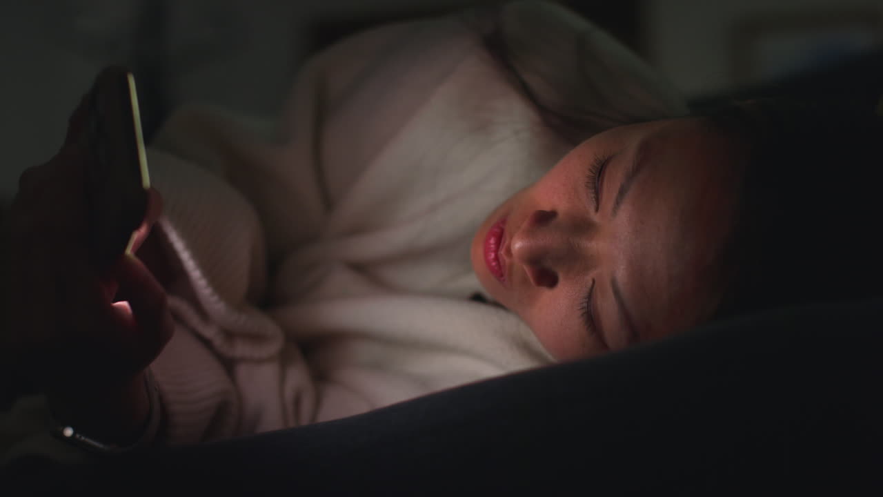 집에서 저녁을 보내고 소파에 누워 휴대전화를 들고 인터넷이나 소셜 미디어를 스크롤하는 여성의 클로즈업 11