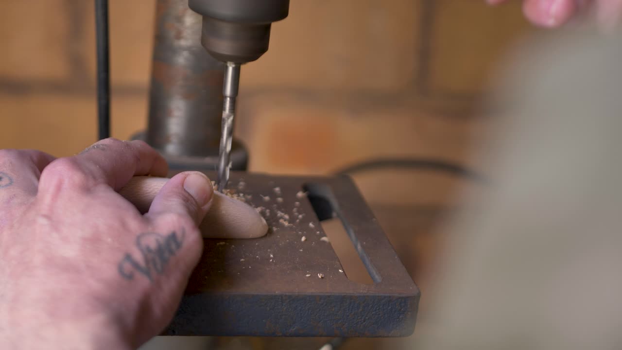 Slow motion close-up of man holding block with drill tool twisting into wooden climbing hold on machinery workbench in Australian DIY home garage shed in Australia industry construction leisure lumber