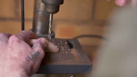 slow motion close-up of man holding block with drill tool twisting into wooden climbing hold on machinery workbench in australian diy home garage shed in australia industry construction leisure lumber