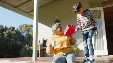 Feliz-Abuela-Birracial-Y-Nieto-Dando-Regalos-En-La-Terraza,-Cámara-Lenta,-Espacio-Para-Copiar