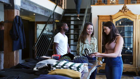 una asistente de ventas sonriente ayudando a una cliente a comprar ropa en una tienda de moda.