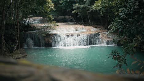 handheld view of a serene waterfall in erawan national park in thailand