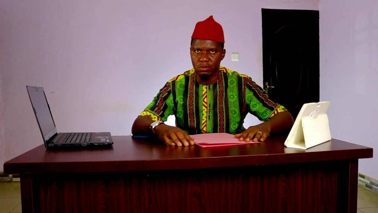 Rozhořčený nigerijský kancelářský podnikatel dramaticky zvedá ruku.