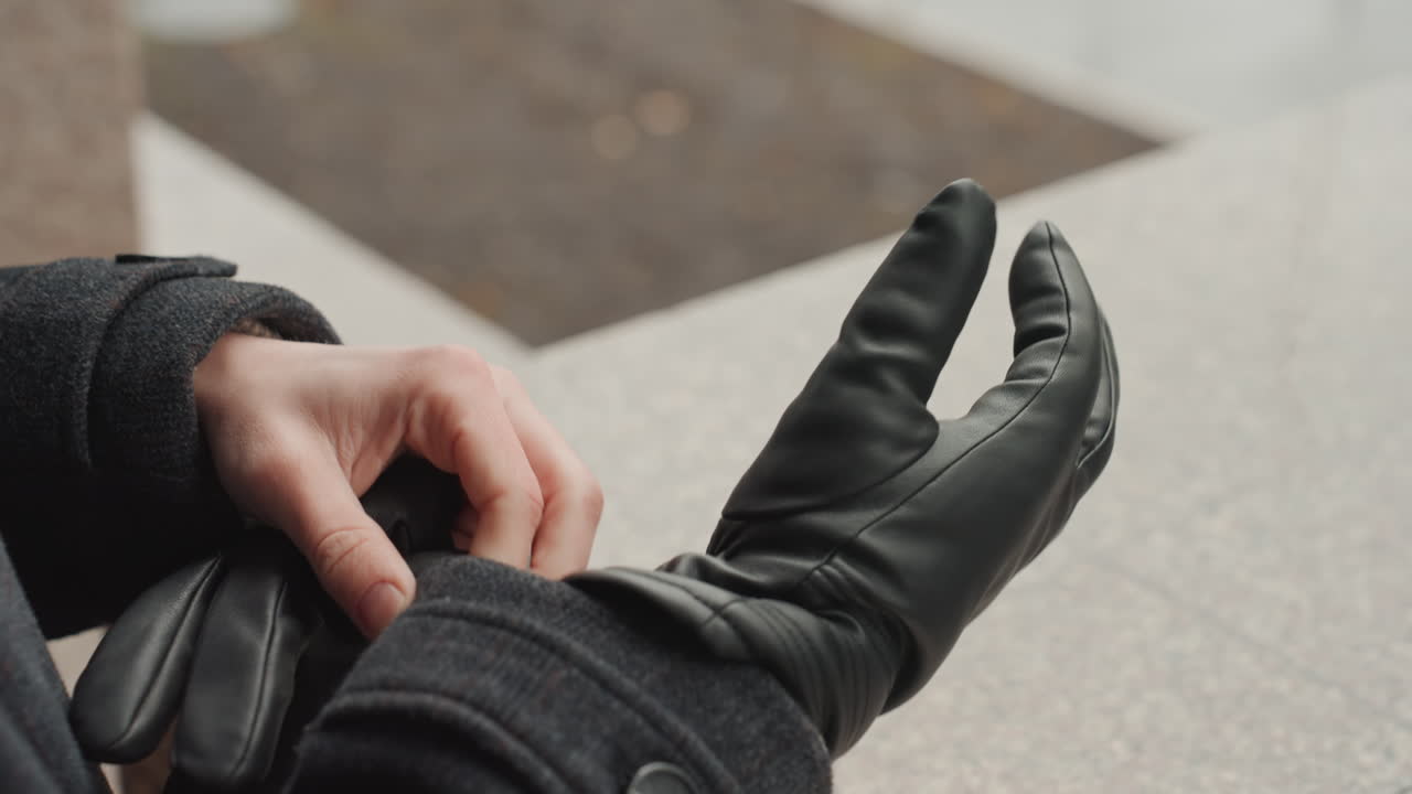 Quiet person dons protective gear. Stealthy individual carefully puts on gloves. Silent individual meticulously and carefully slides protective gloves onto their hands with expertise