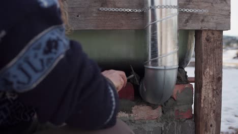 The-Man-is-Filling-in-the-Openings-and-Applying-Cement-Around-the-Chimney-Located-Beneath-the-DIY-Hot-Tub---Close-Up